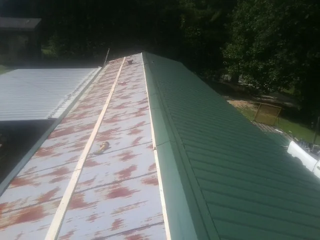Old rusted panels beside newly installed green metal roofing — Wind Damage Roof Repair by Roofing Brothers in Rio Grande