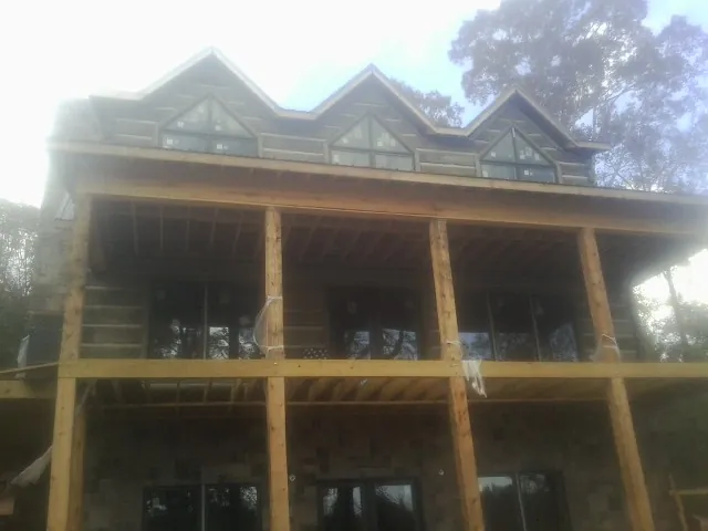 Dormers and porch framing on a large log home under construction — Roof Coating work by our crew in Rio Grande
