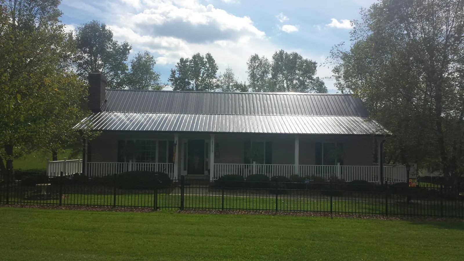 Gray metal roof on a brick ranch with a full width front porch — Gutter Guard Installation work by our crew in Rio Grande