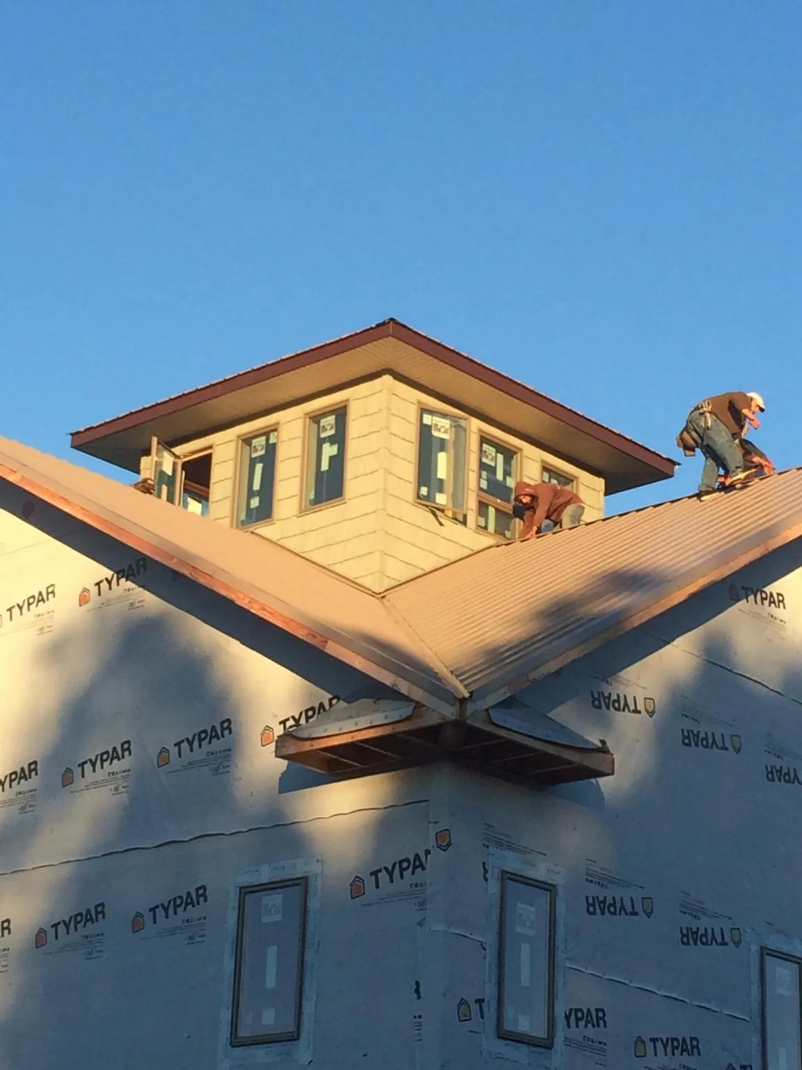 Roofers working around a rooftop cupola on a new metal roof at sunset — Roof Waterproofing in Rio Grande by Roofing Brothers